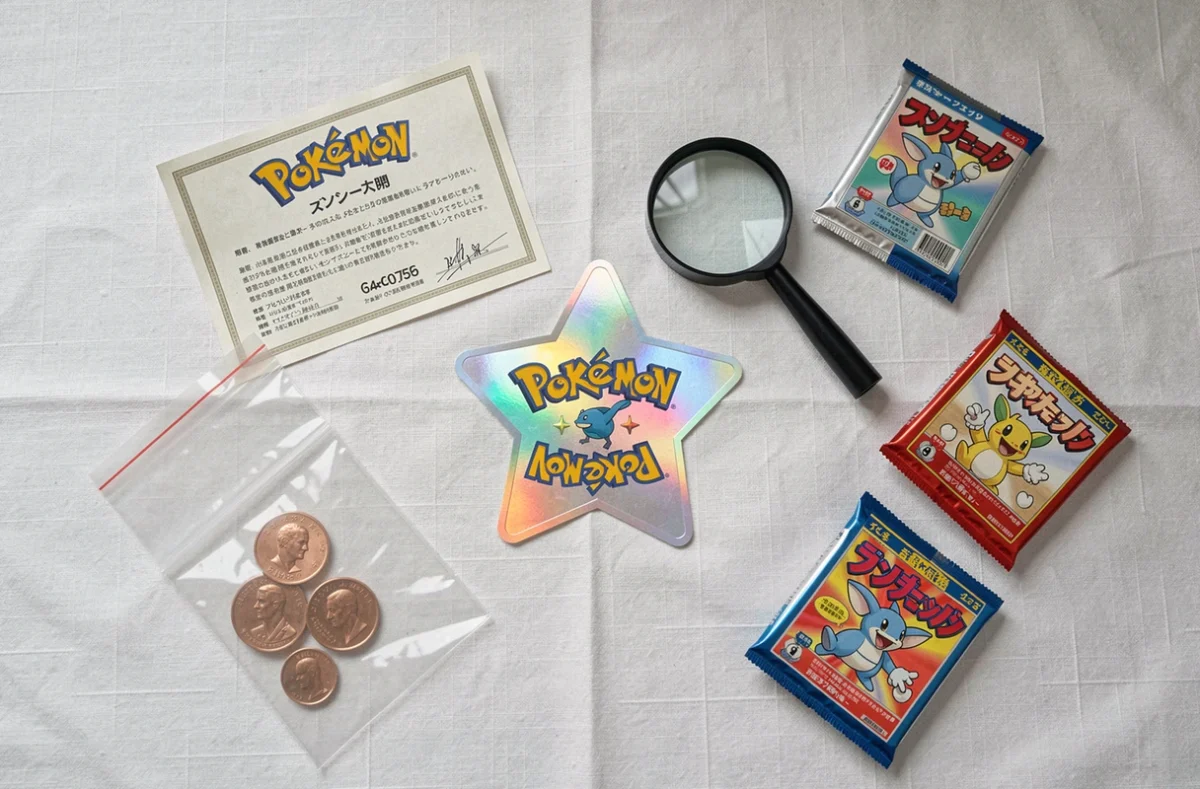 Vue à plat de la carte Celebi Star entourée d'accessoires de collection Pokémon comme une loupe et des pochettes de protection sur lin blanc